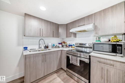 Kitchen featuring wood-finish cabinetry, white countertops, subway tile backsplash, stainless steel appliances, and recessed lighting - 12118 125 Street Nw, Edmonton, AB - Indoor Photo Showing Kitchen With Double Sink