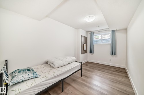 Room featuring wood-finish flooring, white baseboards, and a window with blinds - 12118 125 Street Nw, Edmonton, AB - Indoor