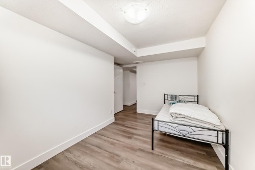 Neutral white wall finishes, wood-finish flooring, and crisp white baseboards define this room - 12118 125 Street Nw, Edmonton, AB - Indoor