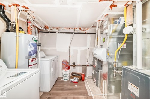 Utility area featuring a water heater, washer, dryer, HVAC system, and exposed ceiling joists with wiring - 12118 125 Street Nw, Edmonton, AB - Indoor Photo Showing Laundry Room