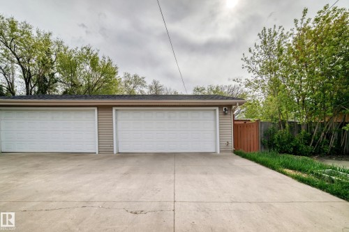 Two-car detached garage featuring horizontal tan siding, white panel doors, and a concrete driveway - 12118 125 Street Nw, Edmonton, AB - Outdoor With Exterior