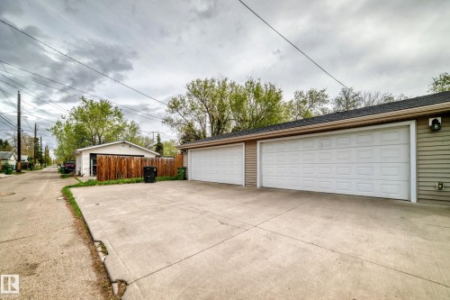 Two-car garage with white paneled garage doors, light-colored siding, and concrete driveway - 12118 125 Street Nw, Edmonton, AB - Outdoor With Exterior