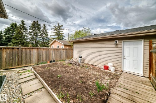 Rear exterior featuring beige horizontal siding, a white door, and an asphalt shingle roof - 12118 125 Street Nw, Edmonton, AB - Outdoor