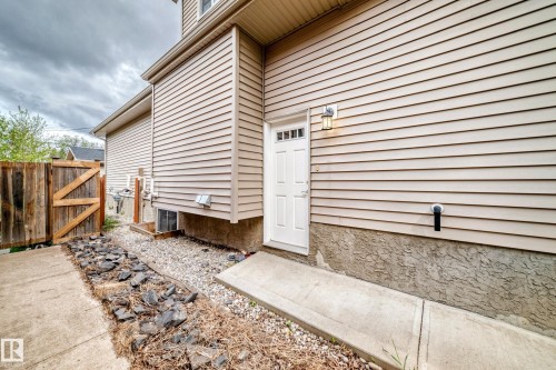 Cream-toned horizontal siding with a white paneled door featuring a transom window - 12118 125 Street Nw, Edmonton, AB - Outdoor With Exterior