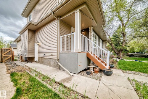 Exterior elevation featuring light-toned horizontal siding, a covered porch with white railings, and a side entry door - 12118 125 Street Nw, Edmonton, AB - Outdoor