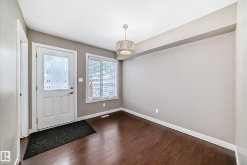 Entryway featuring a white door with decorative glass inserts, dark wood-finish flooring, and a contemporary pendant light fixture - 12118 125 Street Nw, Edmonton, AB - Indoor Photo Showing Other Room