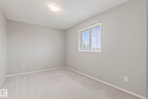 Neutral-toned carpeting with light gray walls, a flush-mount ceiling light, and a white window with horizontal blinds - #80 4350 23St Nw, Edmonton, AB - Indoor Photo Showing Other Room