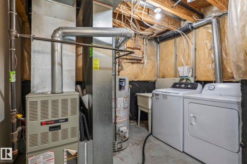 Utility space featuring a furnace, water heater, washer, dryer, and a utility sink - #80 4350 23St Nw, Edmonton, AB - Indoor