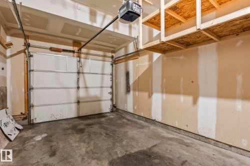 Garage space with concrete flooring, a paneled overhead door, and an automatic door opener - #80 4350 23St Nw, Edmonton, AB - Indoor Photo Showing Garage