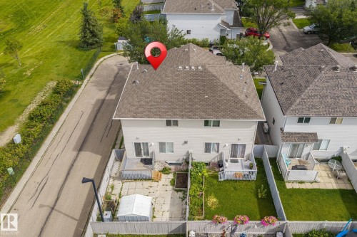Shingled roof, light-colored siding, private backyard, upper-level windows, ground-level patio access - #80 4350 23St Nw, Edmonton, AB - Outdoor With Deck Patio Veranda