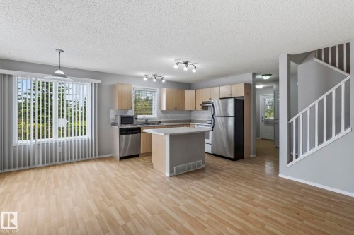 Kitchen with light wood-finish flooring, stainless steel appliances, and wood cabinetry - #80 4350 23St Nw, Edmonton, AB - Indoor Photo Showing Kitchen