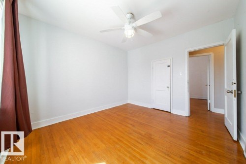 Wood-finish flooring, white walls, white ceiling fan with integrated lighting, multiple doorways with white trim - 7812 128 Avenue Nw, Edmonton, AB - Indoor Photo Showing Other Room