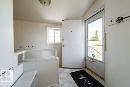 Entryway featuring a white door, window with horizontal blinds, built-in shelving, and coat hooks - 7812 128 Avenue Nw, Edmonton, AB - Indoor