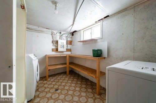 Utility space featuring a single window, built-in wooden shelving, patterned flooring, and an exposed electrical panel - 7812 128 Avenue Nw, Edmonton, AB - Indoor Photo Showing Laundry Room