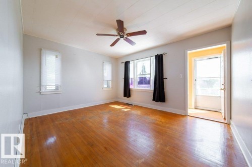 Hardwood flooring, multiple windows, ceiling fan, white paneled ceiling, and a white entry door - 7812 128 Avenue Nw, Edmonton, AB - Indoor Photo Showing Other Room