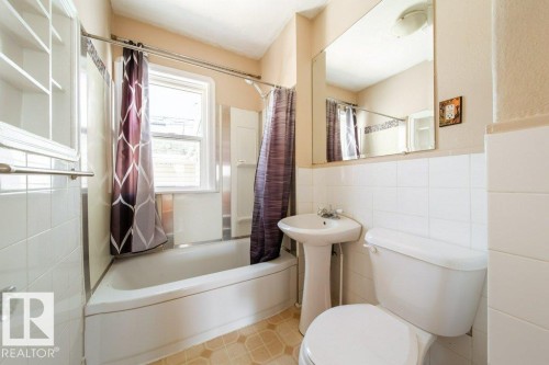 White tiled walls with a built-in bathtub - 7812 128 Avenue Nw, Edmonton, AB - Indoor Photo Showing Bathroom
