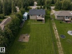 Expansive green lawn featuring a raised garden bed and a dedicated fire pit area - 