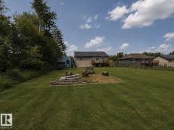 Expansive green lawn with a dedicated fire pit area - 