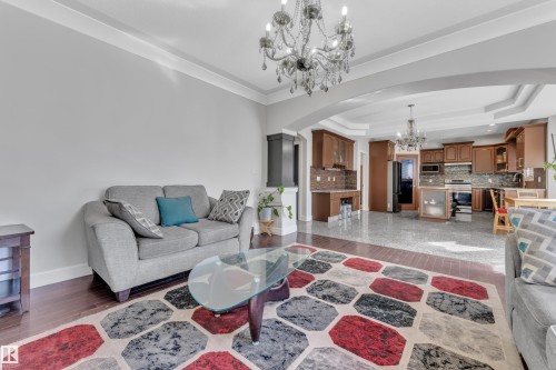 Hardwood flooring, crown molding, arched entryway, tray ceiling, and full kitchen with wood cabinetry - 10915 175 Avenue Nw, Edmonton, AB - Indoor Photo Showing Living Room