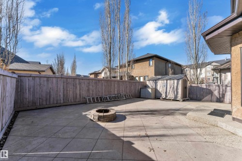 Concrete patio with a built-in stone fire pit, wood privacy fencing, and a storage shed - 10915 175 Avenue Nw, Edmonton, AB - Outdoor With Exterior
