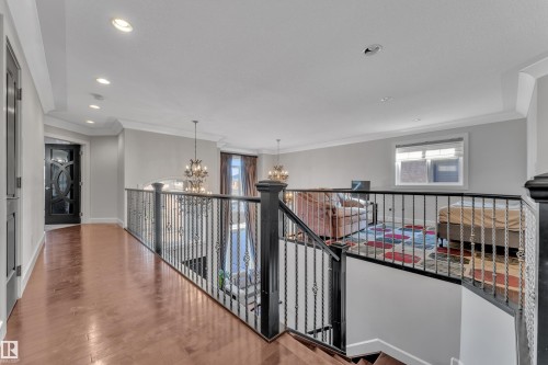 Upper-level landing with wood-finish flooring, recessed lighting, and an ornate wrought-iron railing overlooking the lower level - 10915 175 Avenue Nw, Edmonton, AB - Indoor Photo Showing Other Room
