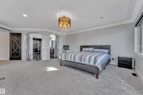 Spacious room featuring light gray carpeting, tray ceiling, and a decorative chandelier - 10915 175 Avenue Nw, Edmonton, AB - Indoor Photo Showing Bedroom