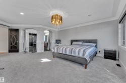 Spacious room featuring light gray carpeting, tray ceiling, and a decorative chandelier - 