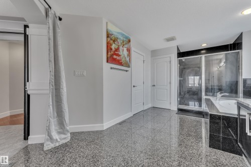 Polished terrazzo flooring, built-in soaking tub, glass-enclosed shower, dual panel doors, and white trim molding - 10915 175 Avenue Nw, Edmonton, AB - Indoor