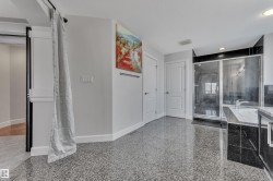 Polished terrazzo flooring, built-in soaking tub, glass-enclosed shower, dual panel doors, and white trim molding - 