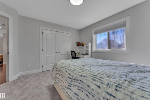 Neutral wall paint, light-toned carpet, double closet doors, white window trim, and overhead lighting - 10915 175 Avenue Nw, Edmonton, AB - Indoor Photo Showing Bedroom