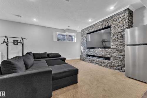 Stacked stone accent wall with integrated media niche, recessed lighting, and crown molding - 10915 175 Avenue Nw, Edmonton, AB - Indoor With Fireplace