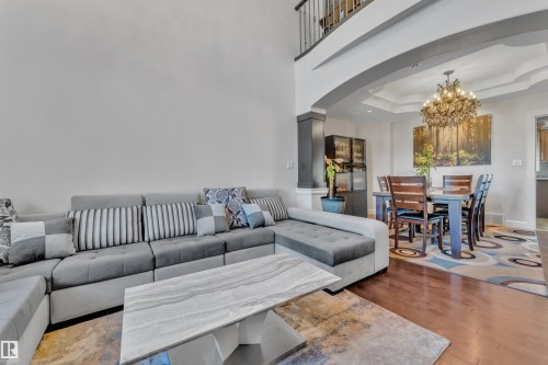 Hardwood-style flooring throughout, arched entryway, tray ceiling with chandelier, and built-in cabinetry - 10915 175 Avenue Nw, Edmonton, AB - Indoor Photo Showing Living Room