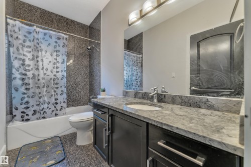 Bathroom featuring a vanity with an integrated sink, a dark wood-finish cabinet, and a stone countertop - 10915 175 Avenue Nw, Edmonton, AB - Indoor Photo Showing Bathroom