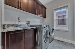Built-in cabinetry with a sink, stone countertop, upper storage cabinets, and a window - 