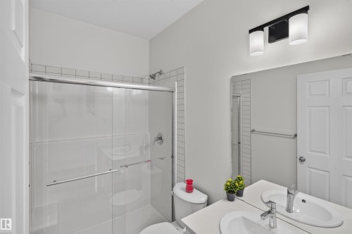 Dual vanity with undermount sinks, chrome fixtures, and a large wall-mounted mirror - 1676 27 Street Nw, Edmonton, AB 