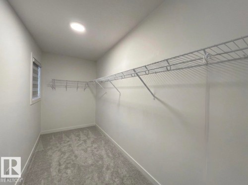 Recessed ceiling lighting, window with horizontal blinds, gray carpet, white walls, and built-in wire shelving - 1676 27 Street Nw, Edmonton, AB 