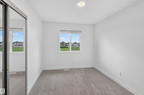 Neutral-toned carpet flooring, white walls, and a single window with a white frame - 1676 27 Street Nw, Edmonton, AB 