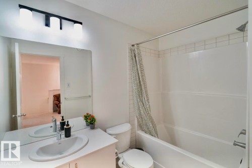 White vanity with integrated sink, chrome faucet, and expansive wall-mounted mirror - 1676 27 Street Nw, Edmonton, AB 
