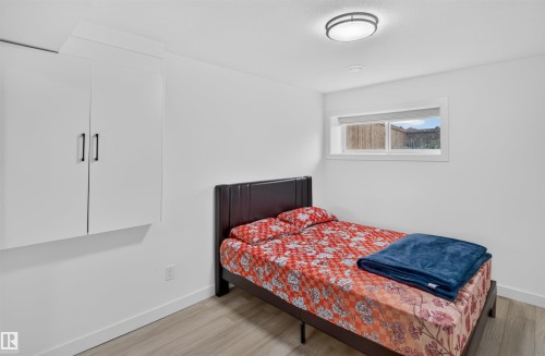 White wall-mounted cabinetry with matte black hardware, wood-finish flooring, and a flush-mount ceiling light - 1676 27 Street Nw, Edmonton, AB 