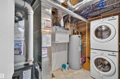 Installed stacked laundry appliances, water heater, and mechanical systems - 1676 27 Street Nw, Edmonton, AB 