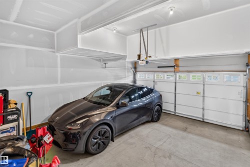 Attached garage featuring concrete flooring and a paneled garage door with upper window inserts - 1676 27 Street Nw, Edmonton, AB 