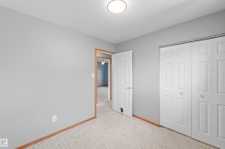 Neutral gray wall paint, patterned carpeting, natural wood trim, overhead flush-mount lighting, and bi-fold closet doors - 