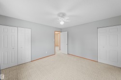 Neutral tone walls, ceiling fan with integrated lighting, paneled bifold closet doors, and light-toned carpet flooring - 
