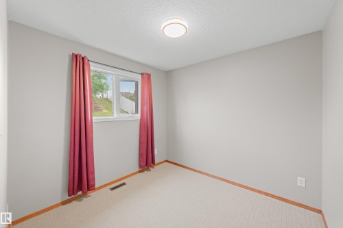 Neutral wall color, carpet flooring, wood trim, flush mount ceiling light, and a window - 14538 37 Street Nw, Edmonton, AB 
