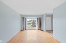 Hardwood-style flooring throughout, bay window with light-filtering curtains, and a white paneled door - 
