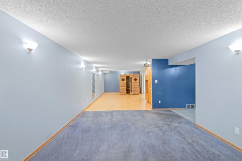 Recessed wood-clad sauna, built-in wood cabinetry, light wood-finish flooring, blue accent wall, and wall-mounted sconces - 14538 37 Street Nw, Edmonton, AB 