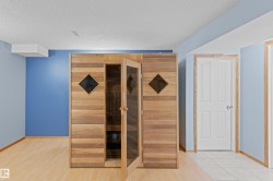 Wood-paneled sauna featuring a glass door and diamond-shaped windows, set against a blue wall - 