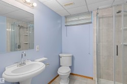 Pedestal sink with chrome fixtures, glass shower enclosure, and tiled flooring - 