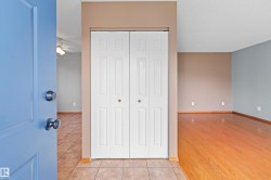 Entryway featuring tile flooring, a bi-fold closet, and a light blue door, opening to a room with wood-finish flooring and a ceiling fan - 