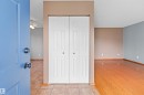Entryway featuring tile flooring, a bi-fold closet, and a light blue door, opening to a room with wood-finish flooring and a ceiling fan - 14538 37 Street Nw, Edmonton, AB 